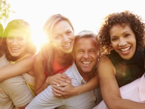 Portrait Of Mature Men Giving Women Piggy Backs, Smiling To Camera