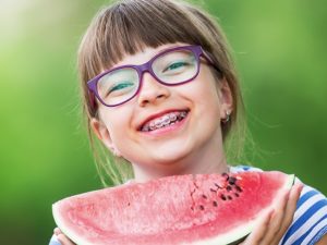 girl with braces smiling and eating watermelon
